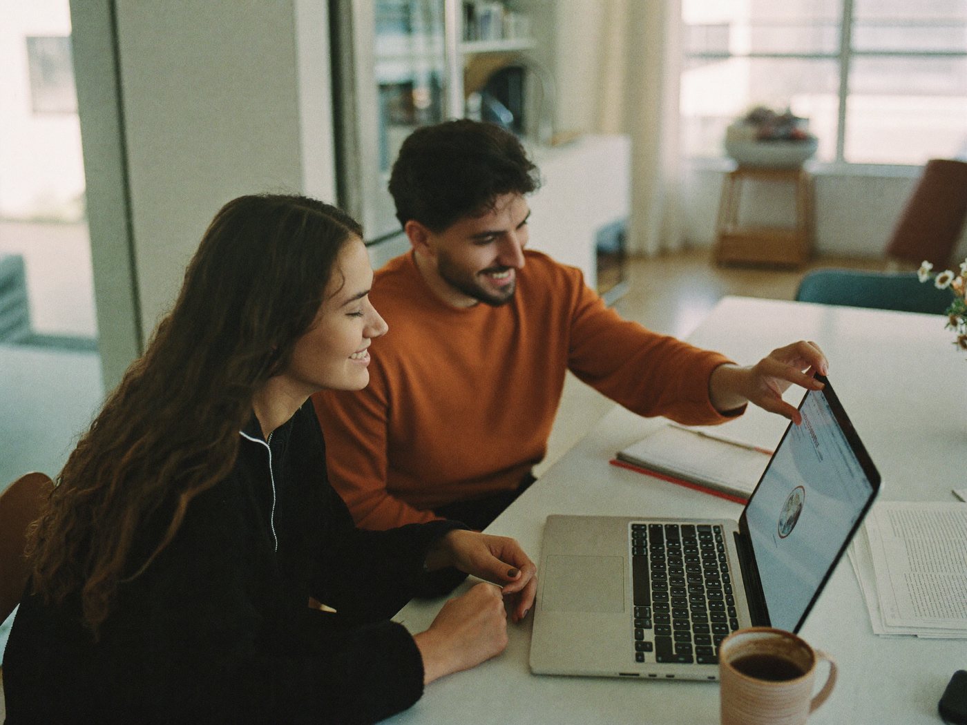 Pareja joven hispana revisando juntos sus opciones en la computadora